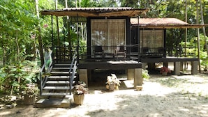 A rustic wooden structure with a staircase leading to a covered seating area, surrounded by dense greenery. - Riviera Resort (Manmunai North)