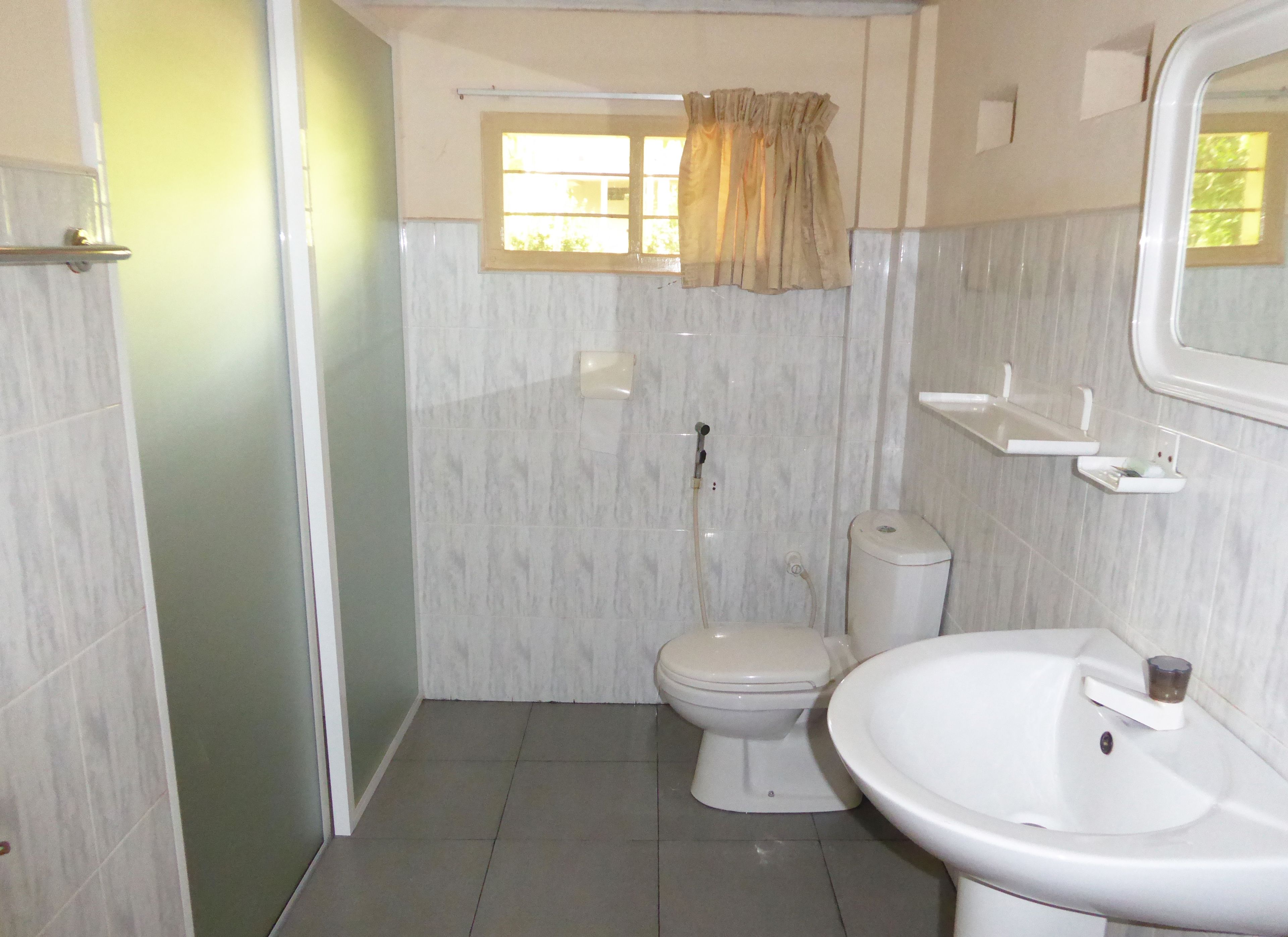 Une salle de bain équipée de toilettes, d’un lavabo et d’une douche.