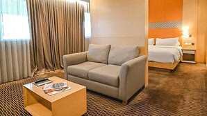 A hotel room with a sofa, a coffee table, a bed, and a nightstand.