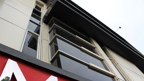 A building with a modern architectural style, featuring large windows and a prominent red and white sign. - Amaliun Hotel (Medan)
