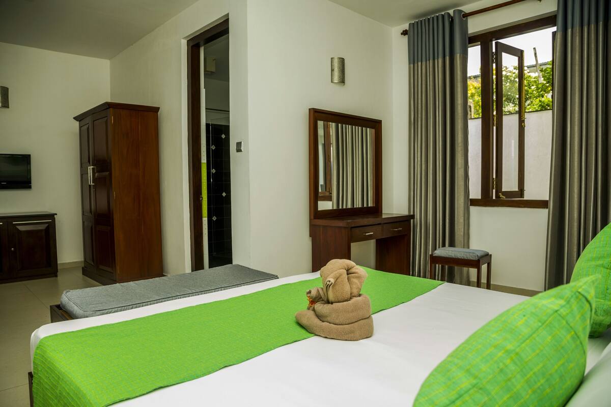 Habitación de hotel con cama, escritorio, espejo y televisión.