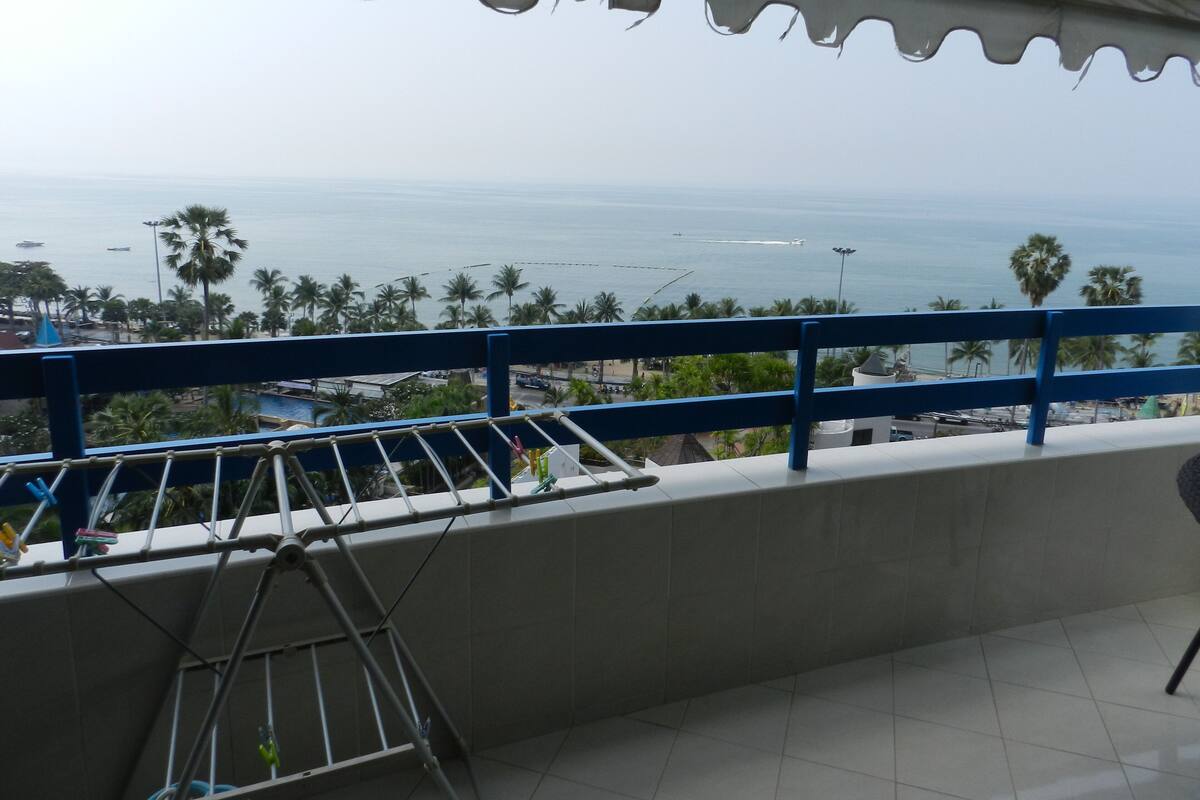 A balcony with a view of the sea and palm trees.