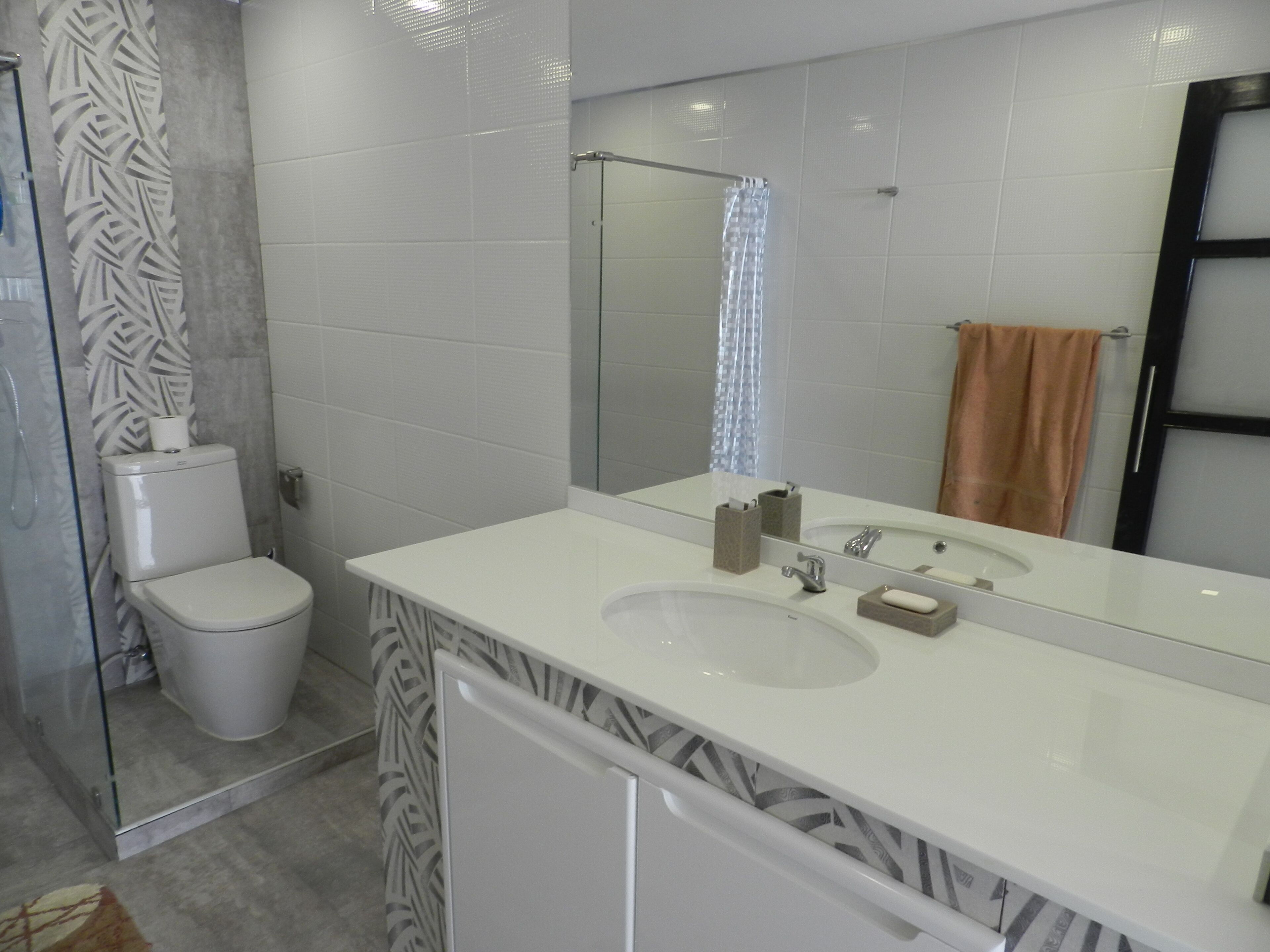 Ein modernes Badezimmer mit einem weißen Waschbecken, Spiegel und WC.