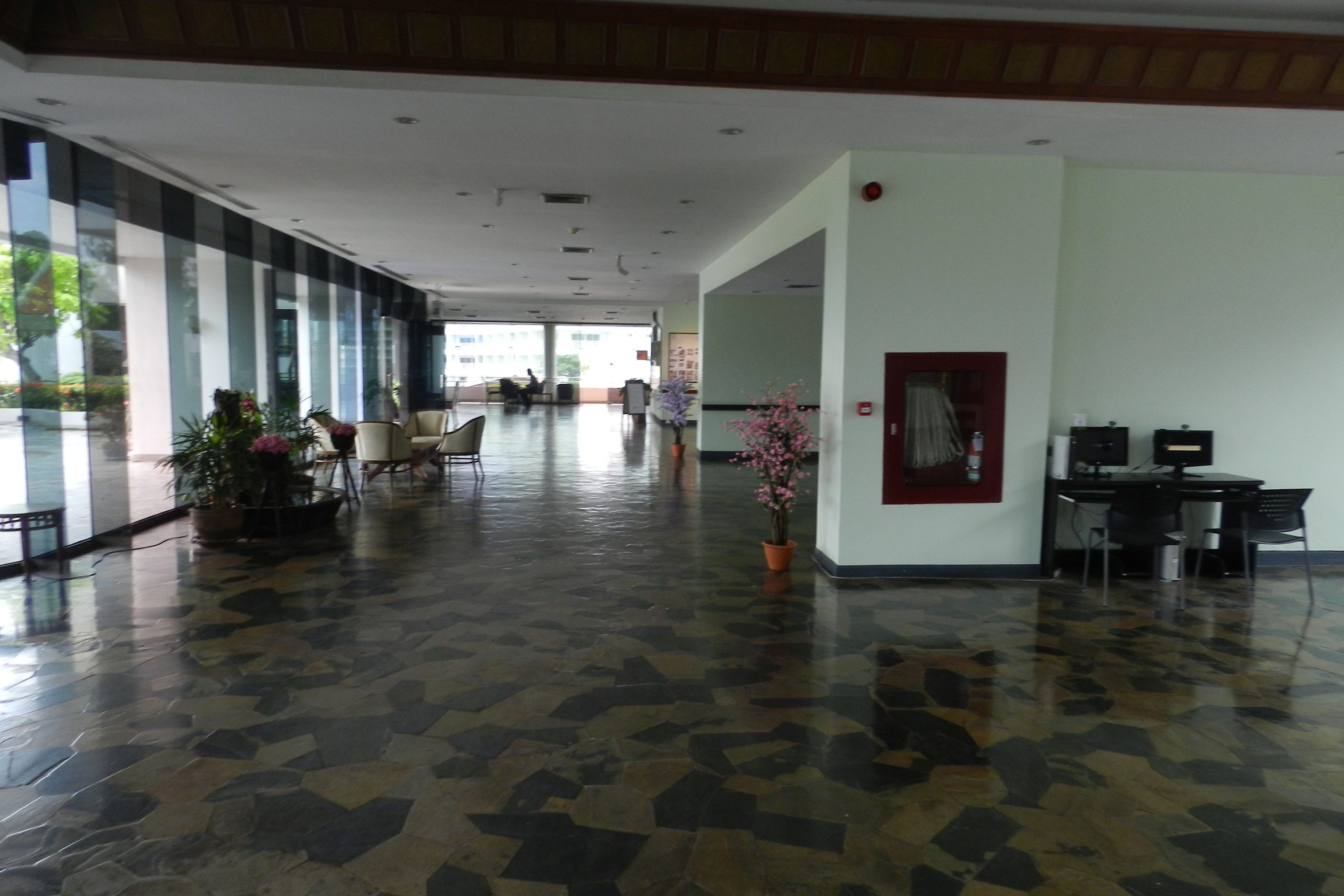 A spacious lobby with a checkered floor, potted plants, and a reception desk.