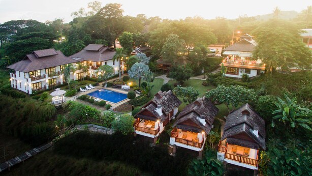 Un complexe hôtelier comprenant plusieurs villas, une piscine et une végétation luxuriante.