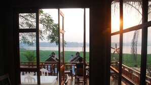 Un espace repas offrant une vue sur une rivière et un paysage verdoyant.