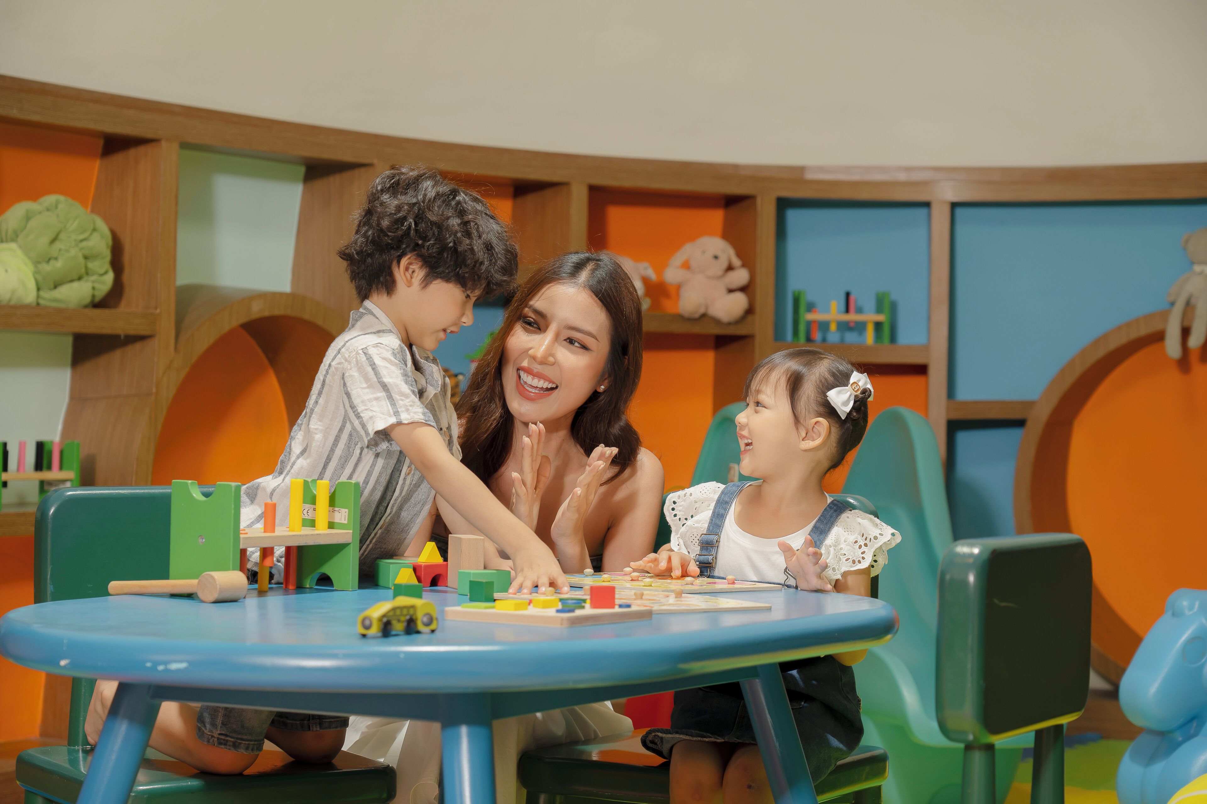 A playroom with a blue table, wooden shelves, and colorful toys.