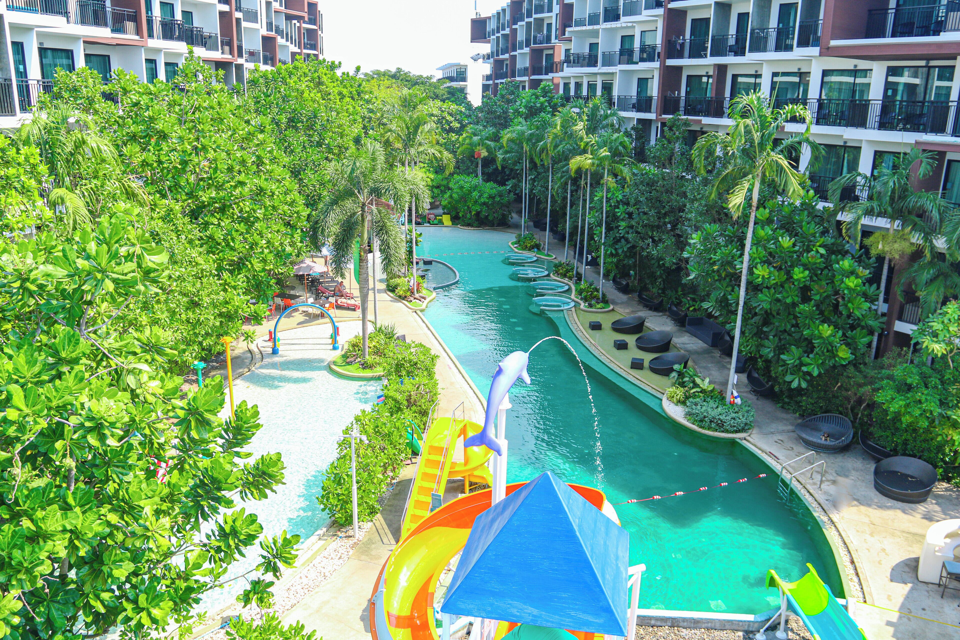 Ein Resort mit Schwimmbad, Wasserrutschen und üppiger Bepflanzung.