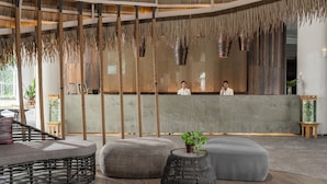 A reception area with a central counter, wooden flooring, and a thatched ceiling.
