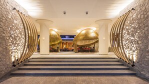 A grand staircase leading to a lobby with stone walls and modern lighting fixtures.