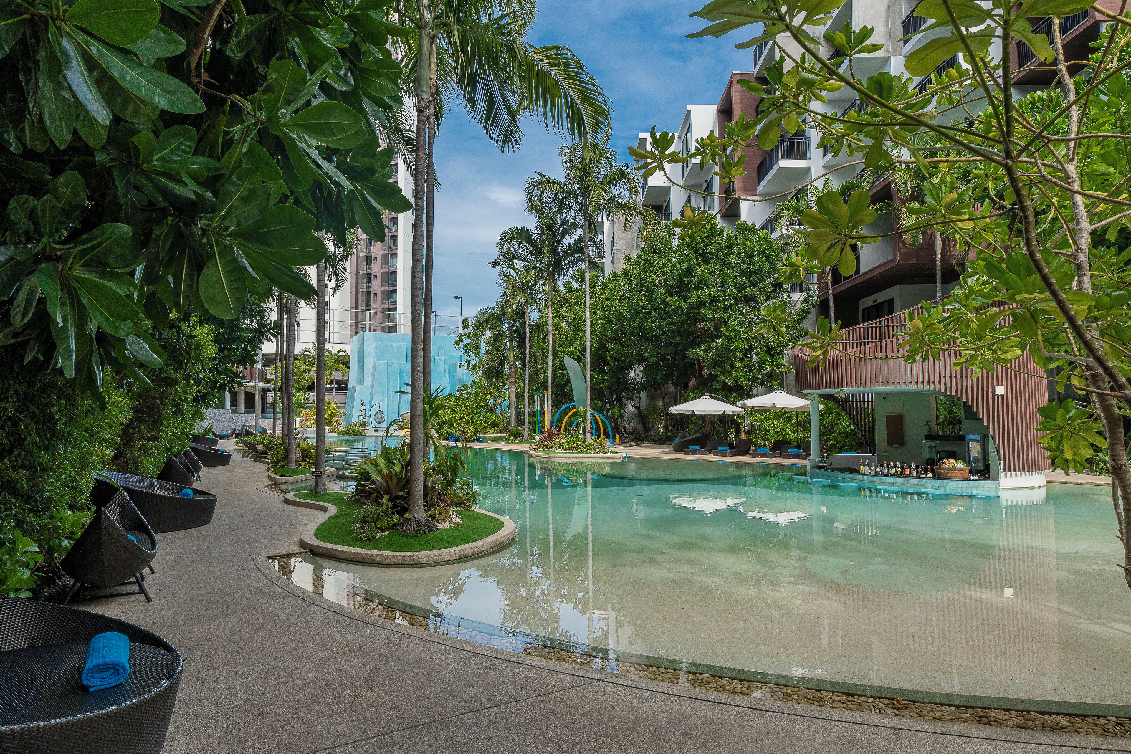 Ein Poolbereich mit Liegestühlen, einer Bar und einem kleinen Wasserfall.