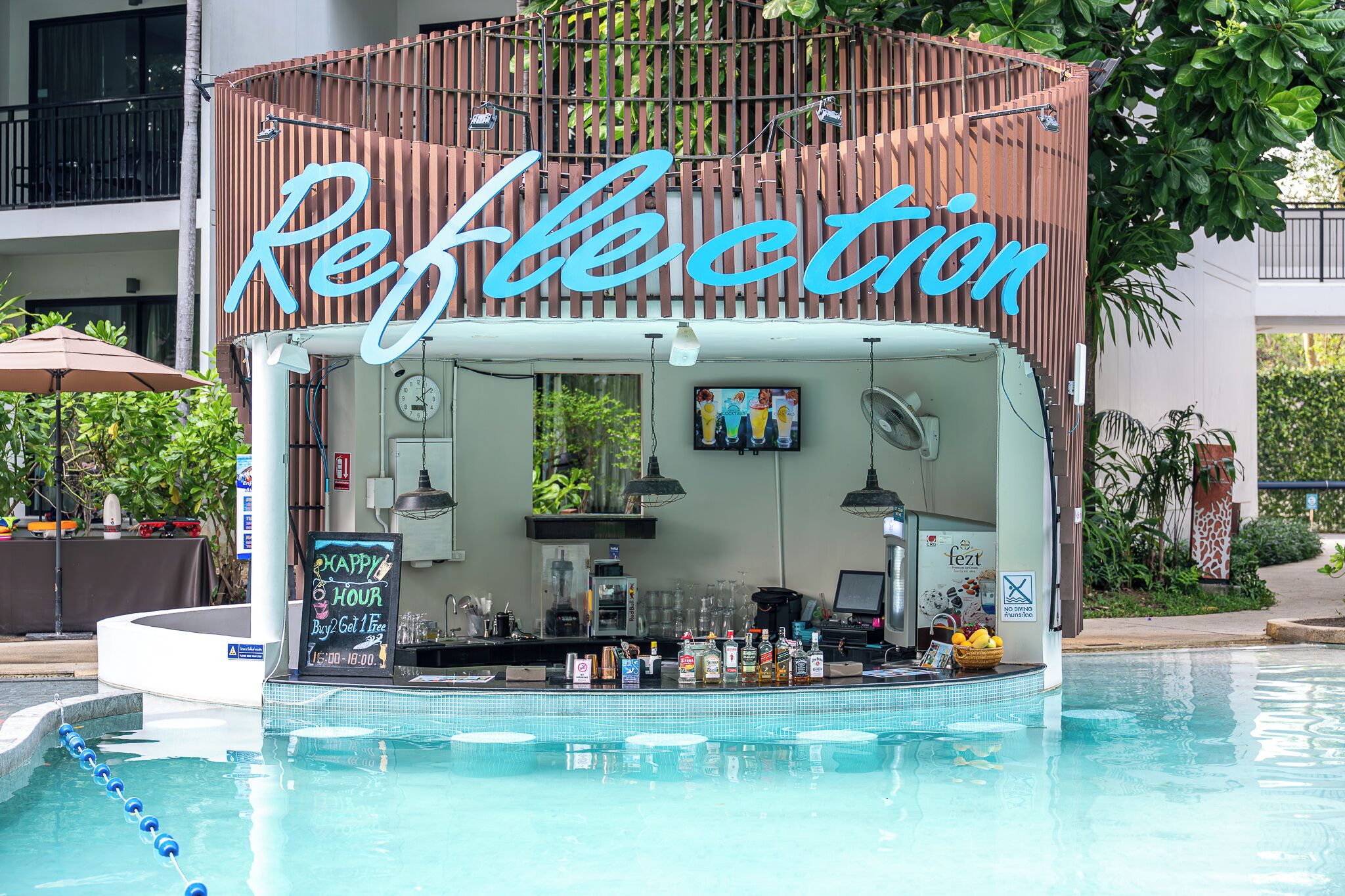 Zona de bar con un letrero que dice "Reflection" y un ambiente junto a la piscina.