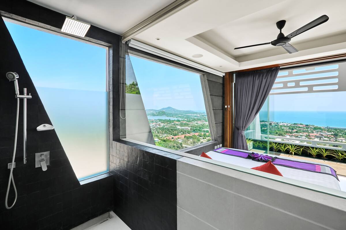 Ein modernes Badezimmer mit großem Fenster, Dusche und Deckenventilator.
