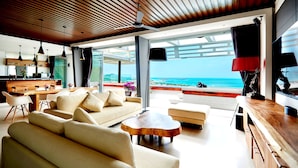 A modern living room with a wooden ceiling, large windows, and a view of the beach. - Aqua Samui Villas (Koh Samui)