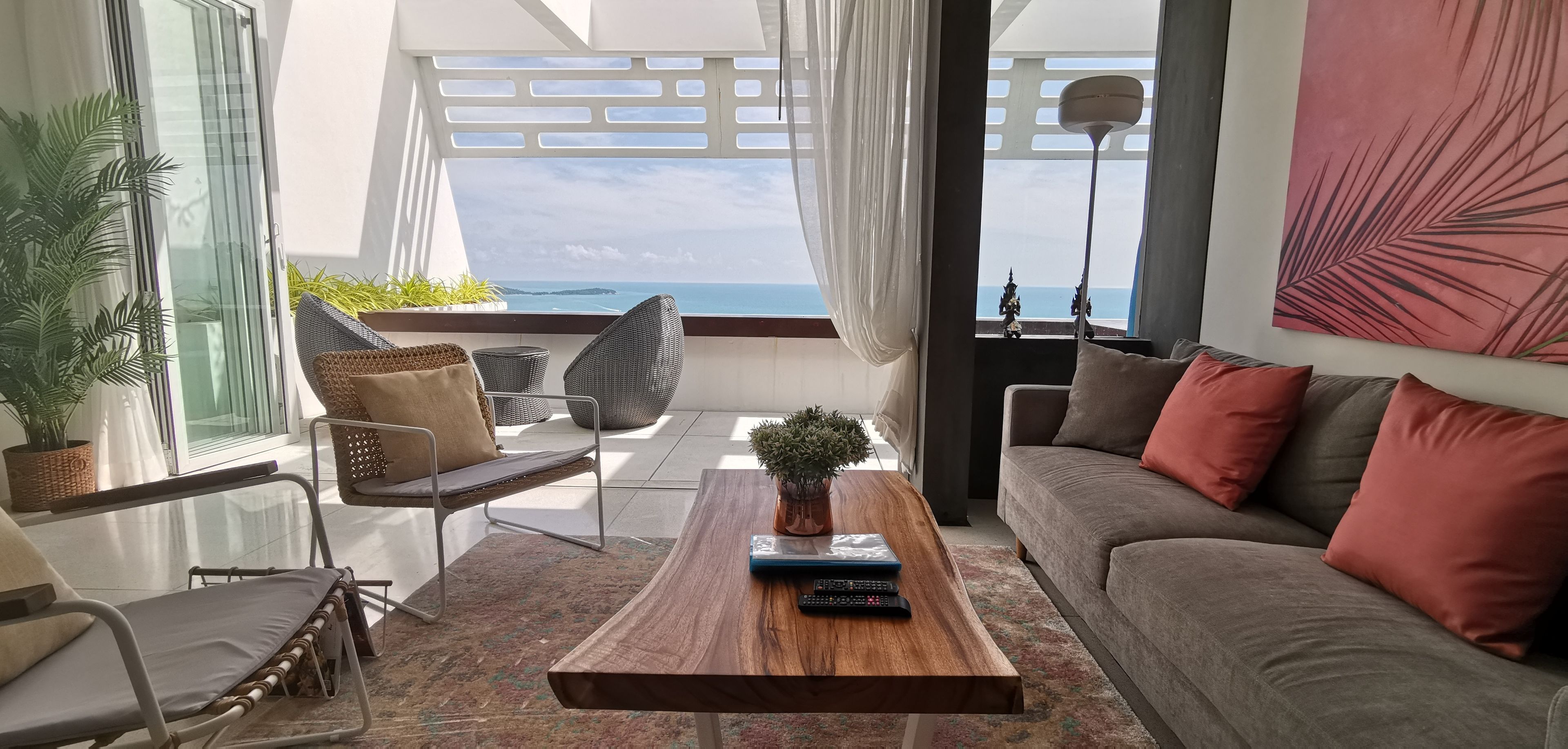 A modern living room with a sofa, chairs, a coffee table, and a view of the sea.