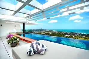 Une piscine à débordement moderne offrant une vue dégagée sur l’océan et le paysage urbain.