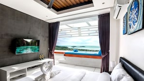 A modern hotel room with a large bed, a TV, a balcony with a view of the sea, and a white console table. - Aqua Samui Villas (Koh Samui)