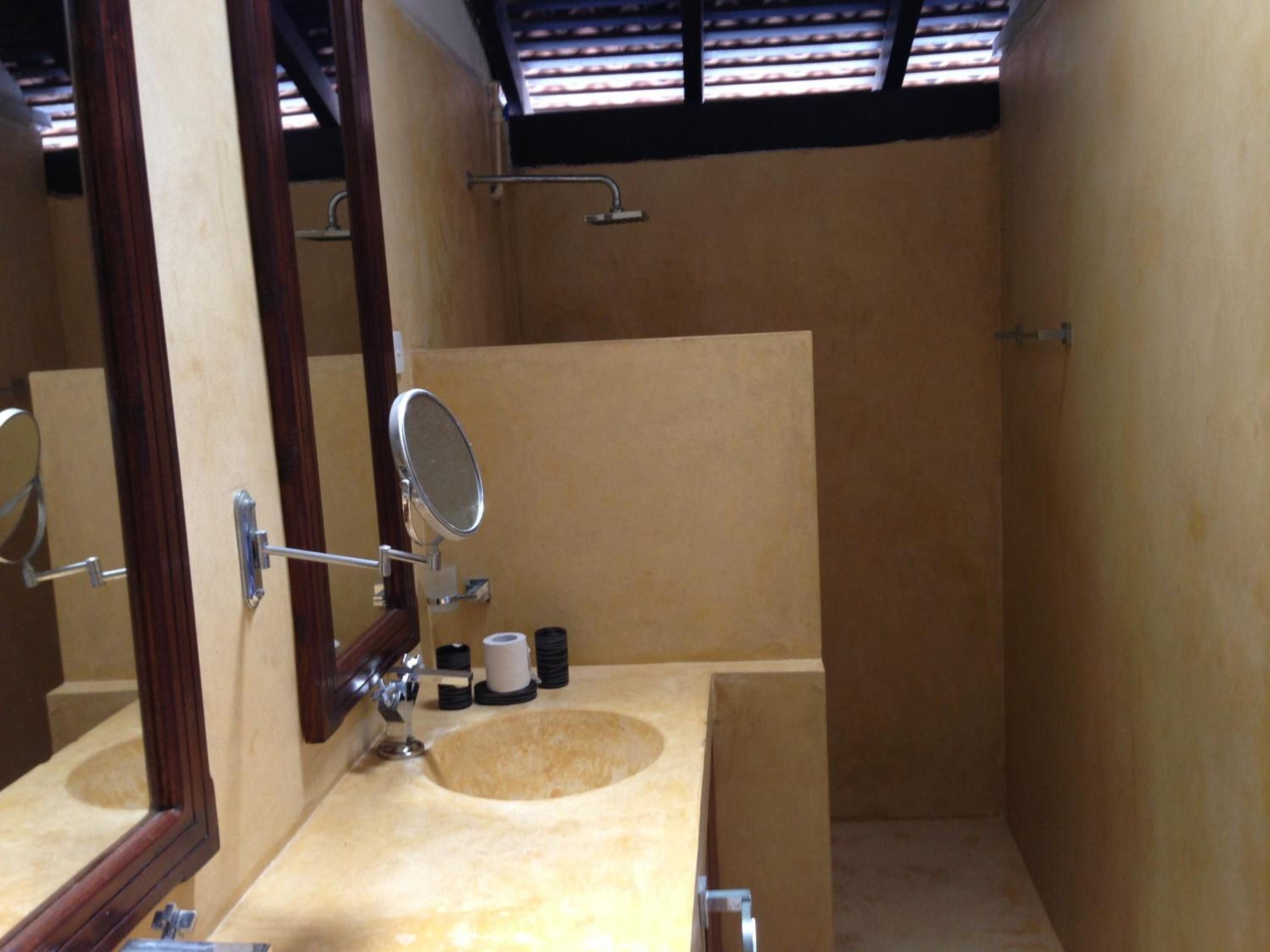 Un baño pequeño, con tocador de madera, un espejo y un lavamanos.
