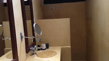 Un baño pequeño, con tocador de madera, un espejo y un lavamanos.