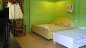 A room with green brick walls, a bed, a chair, and a small table.