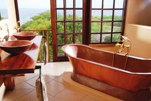 A bathroom with a large bathtub, two bowls, and a view of the ocean. - Deacra Villas By Sol Resorts (Vilanculos)