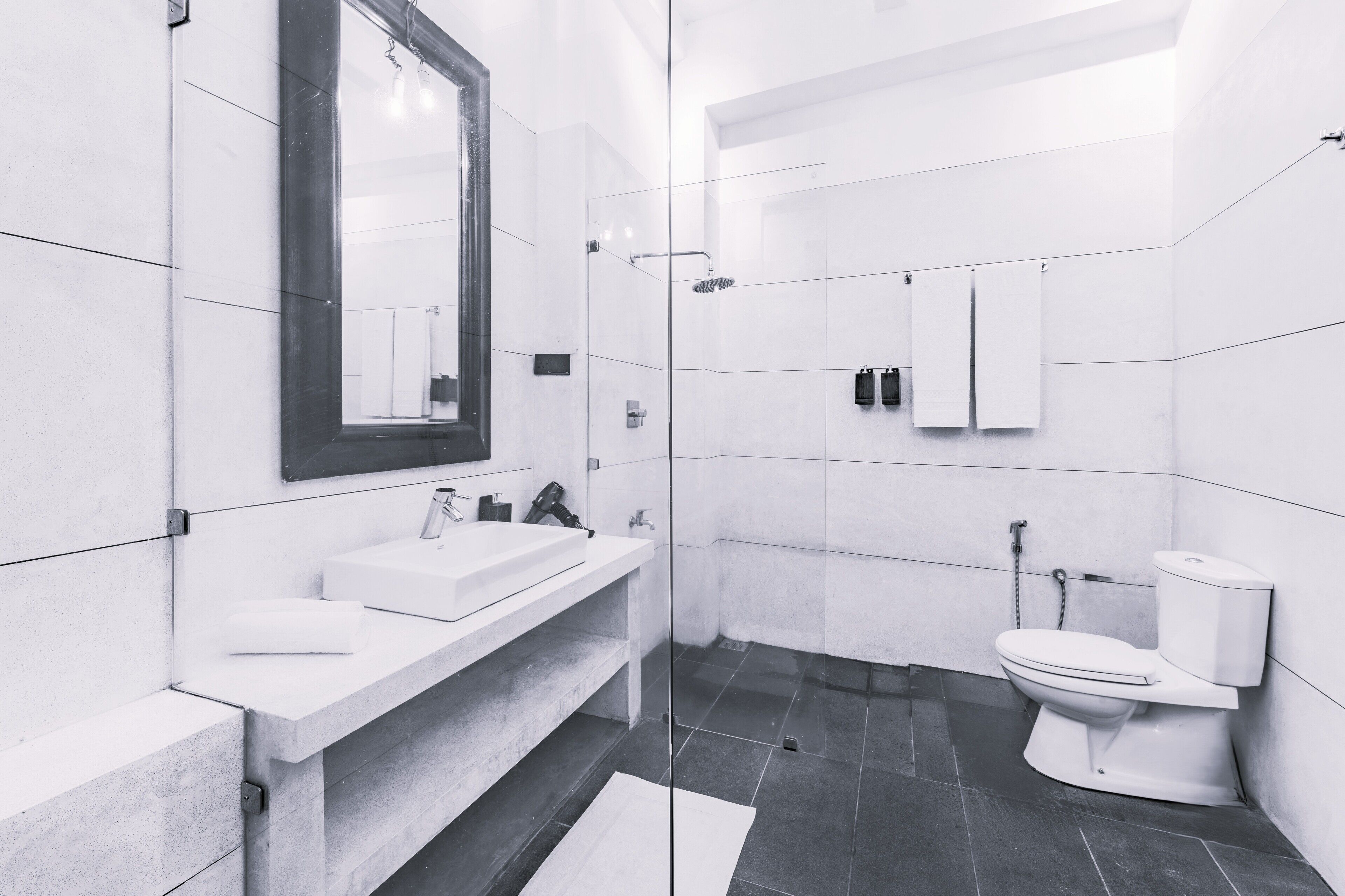 A modern bathroom with a large mirror, a sink, a toilet, and a shower.