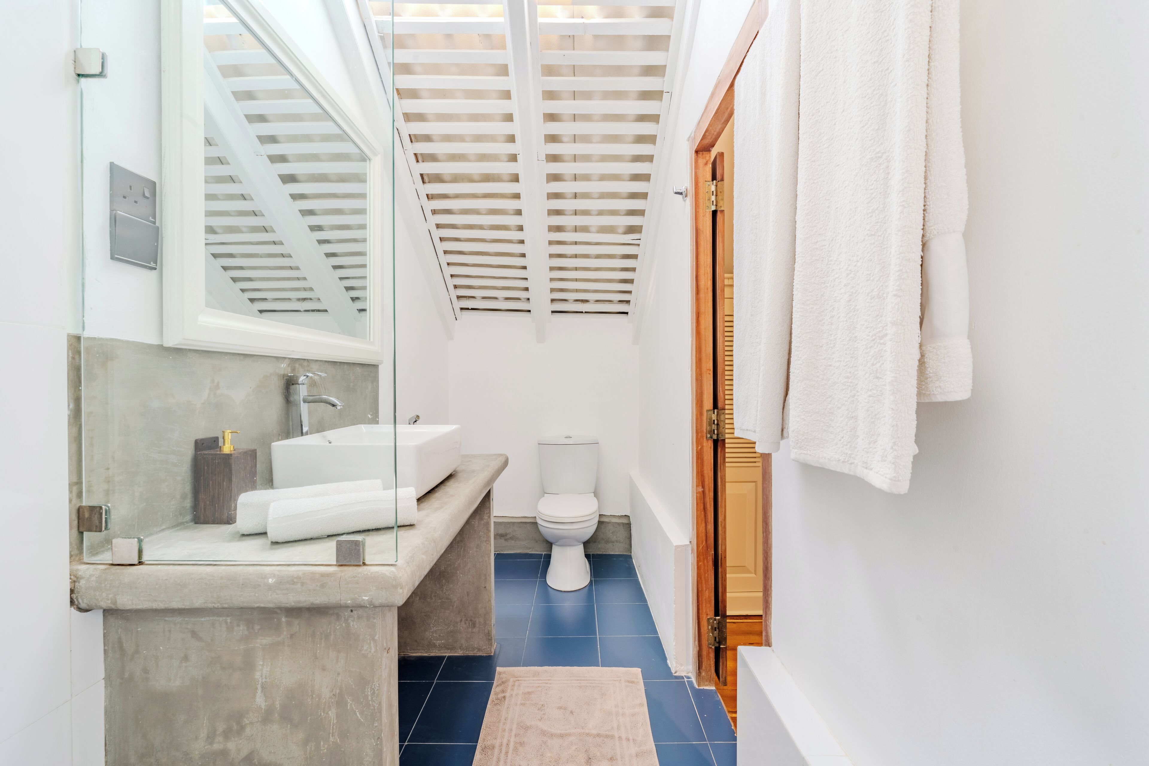 A modern bathroom with a skylight, a bathtub, a toilet, and a sink.