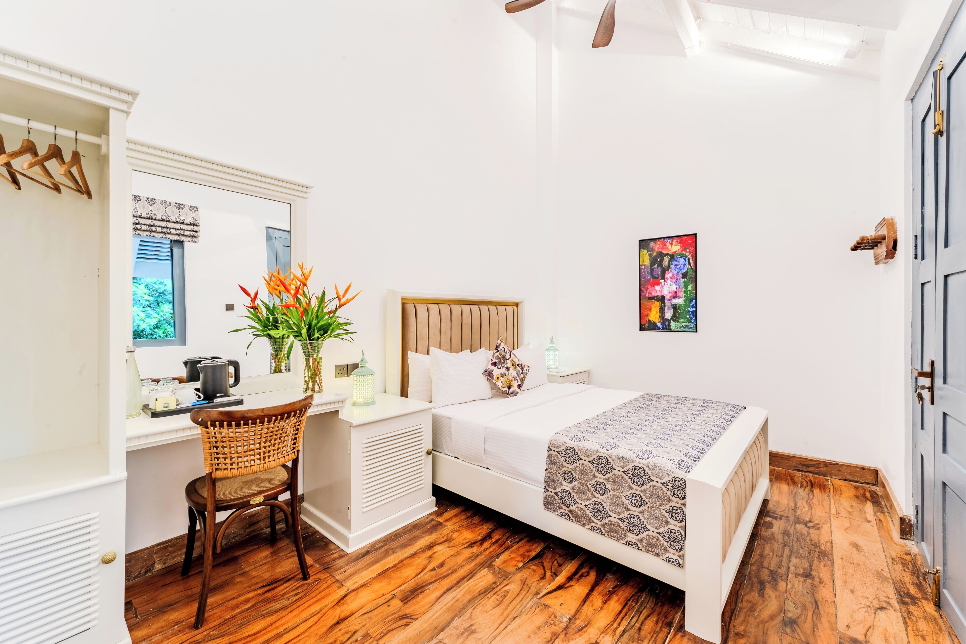 A bedroom with a bed, a desk, a chair, a window, and a door.