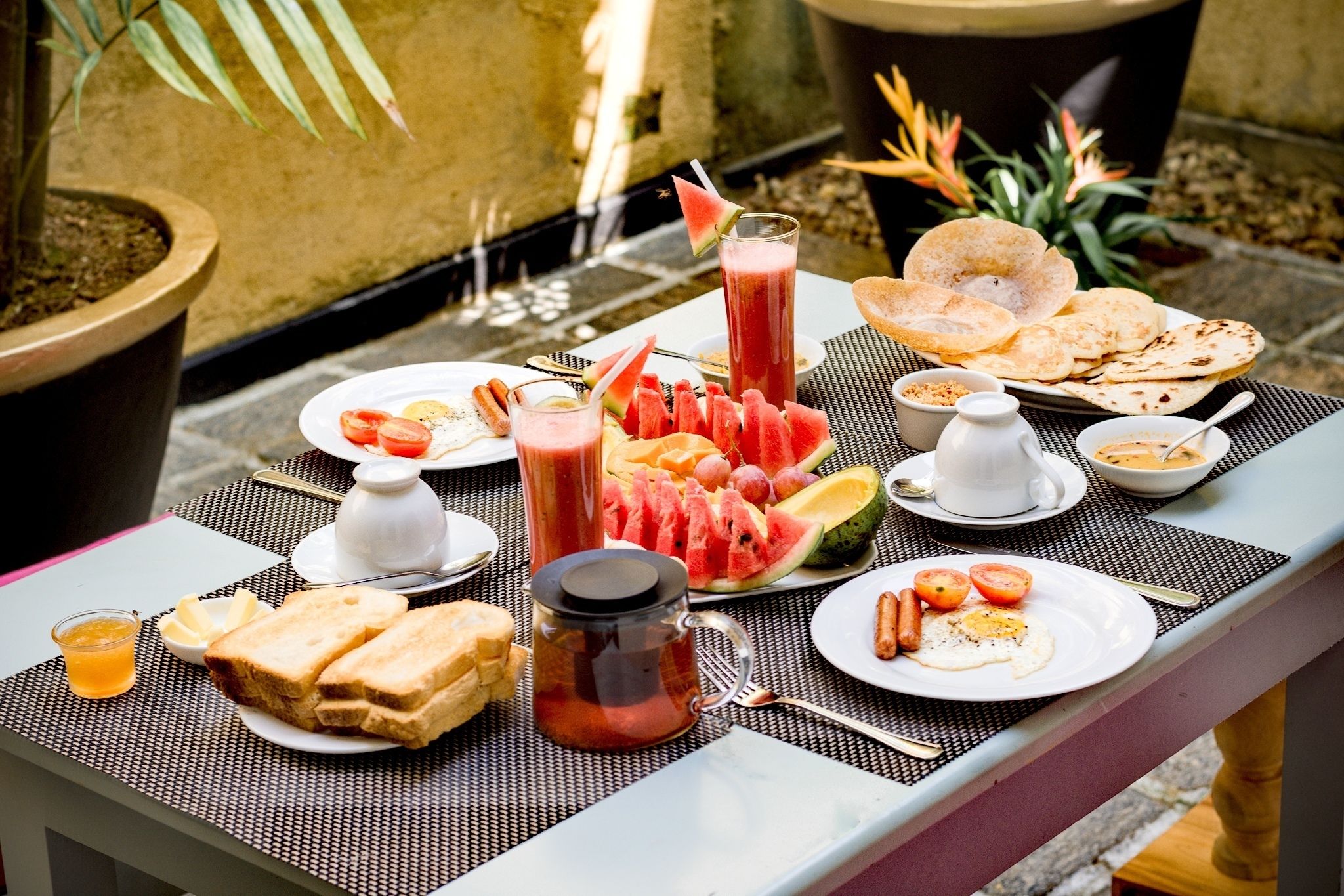 A breakfast table with various food items and drinks, including toast, eggs, and a watermelon dish.