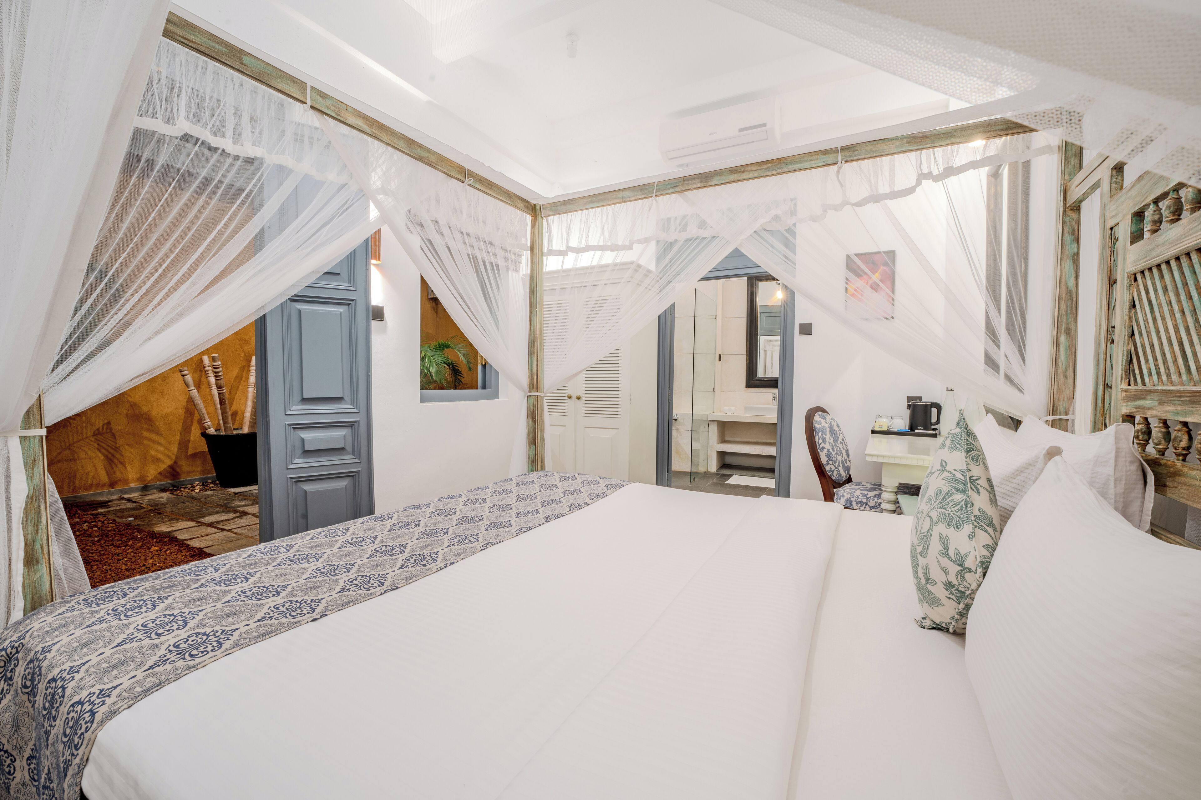 Un dormitorio con una cama grande, cortinas blancas y vistas al exterior.
