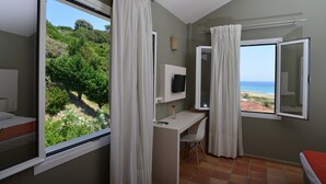 Una habitación con escritorio, televisor y vista al mar.