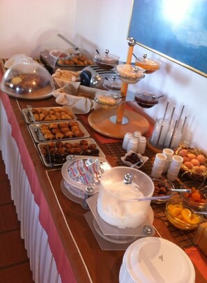 Ett buffébord med olika sorters mat, inklusive bakverk, frukt och tillbehör.