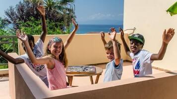 Guests can enjoy a game of chess on the balcony with a view of palm trees and the sky.