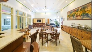 Un comedor amplio con mesas y sillas de madera, un cuadro grande en la pared y un mostrador de buffet con diversos platos.