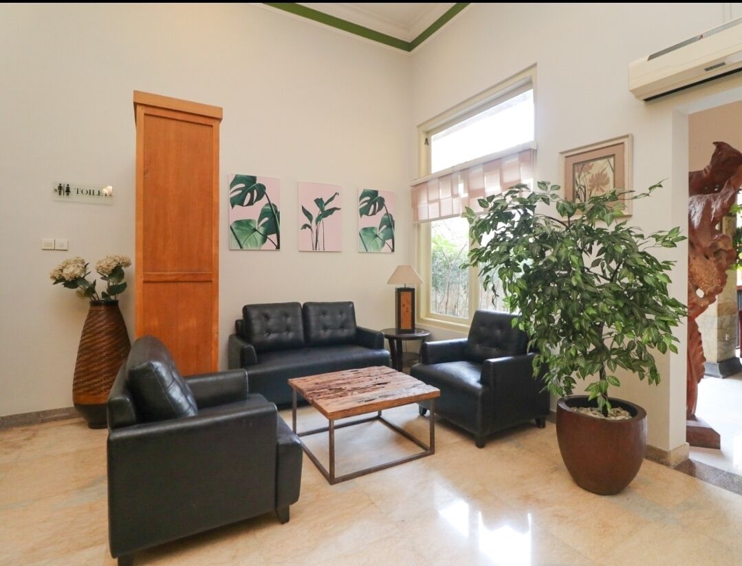 A modern lobby with leather sofas, a coffee table, a large potted plant, and artwork on the walls.