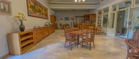 Un'ampia sala da pranzo con tavolo e sedie in legno, un grande quadro appeso al muro e una cucina sullo sfondo.