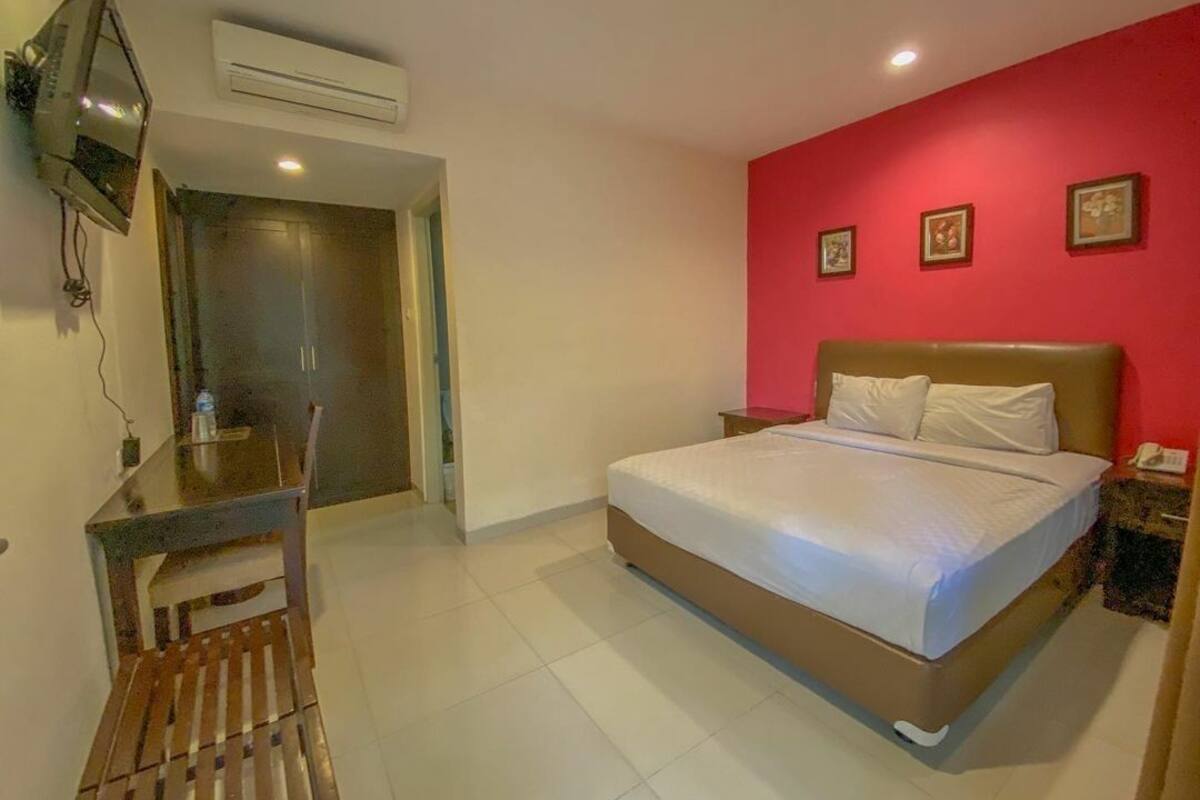 A bedroom with a bed, a desk, and a chair.