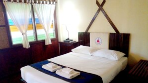 Une chambre d’hôtel avec un lit bien fait, une table de chevet avec une lampe et une fenêtre avec des rideaux.