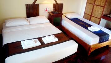 Une chambre d’hôtel avec deux lits, chacun doté de draps blancs et d’une tête de lit en bois. On y trouve une table de chevet avec une lampe, ainsi qu’une petite table avec une télécommande.