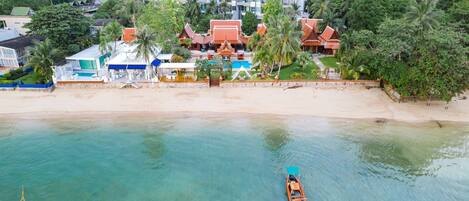 A coastal resort with a swimming pool, beach, and traditional architecture.