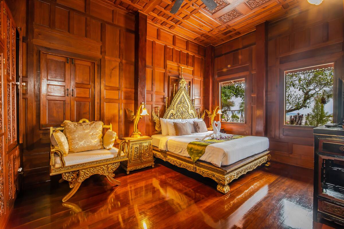 Une chambre traditionnelle en bois, dotée d’un grand lit, d’un coin salon avec un canapé et d’une petite table.