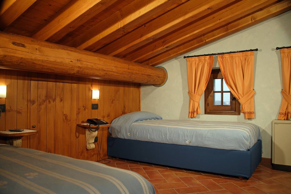 A bedroom with wooden walls, a bed, a small table, and a window with curtains.