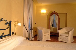 A hotel room with a bed, two chairs, a mirror, and a wall-mounted light. - Agriturismo Macesina (Bedizzole)