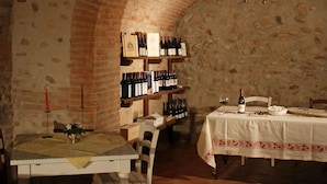 Una bodega rústica con paredes de ladrillo, una mesa de madera y un botellero.
