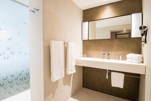 A modern bathroom with a large mirror, a sink, and a shower area. - Simon Hotel (Fort-de-France)