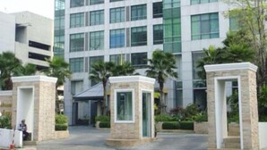 A modern building with a glass facade and a central entrance. - Baan Sathorn Riverfront (Bangkok)