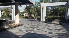 A spacious outdoor area with a patterned floor, large planters, and a covered walkway.