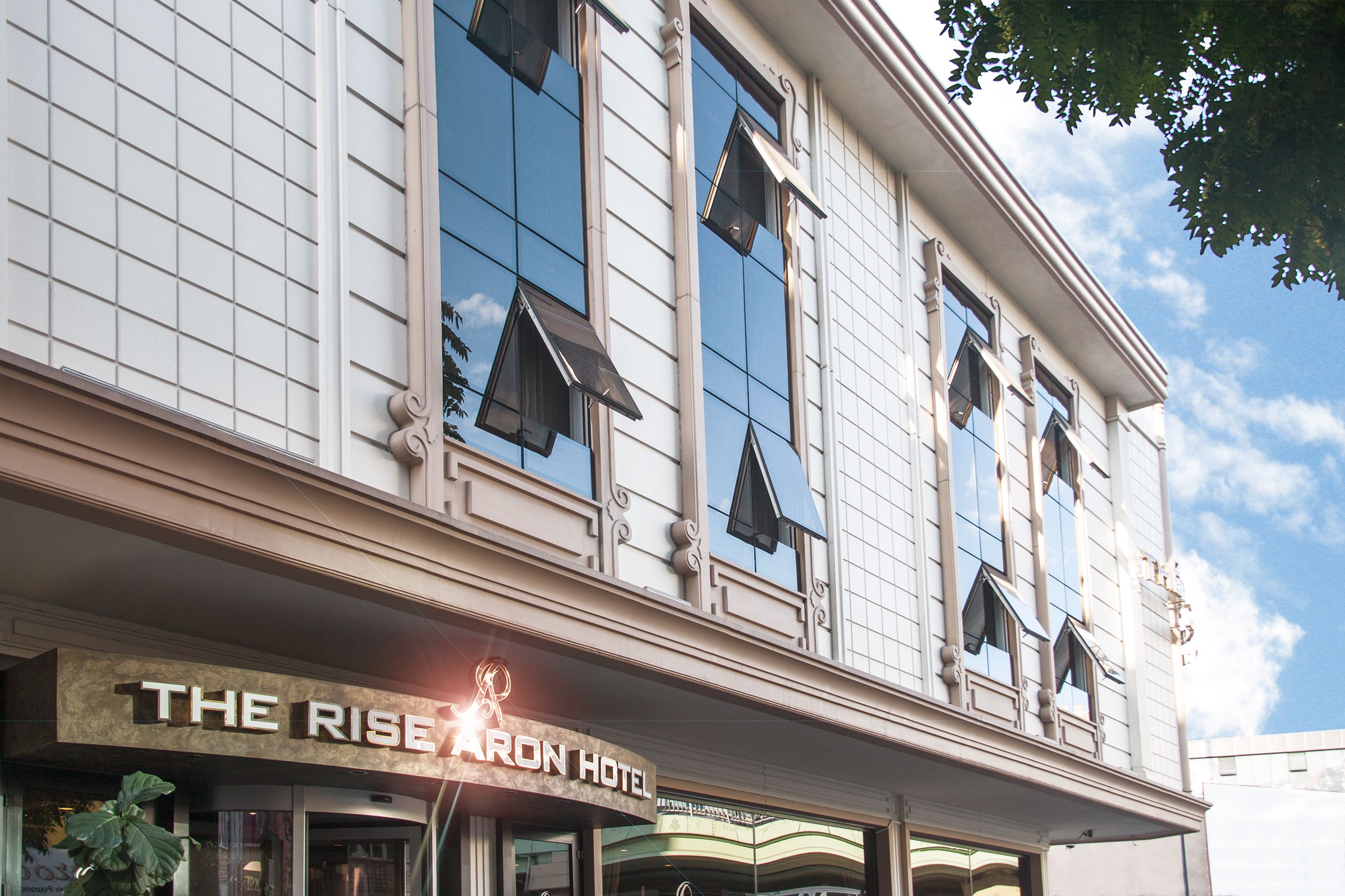 A building with a sign reading "The Rise Aron Hotel".