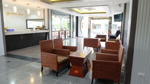 A hotel lobby with wicker furniture, a reception desk, and a large TV screen. - Silom Boutique Hotel Hatyai (Hat Yai)