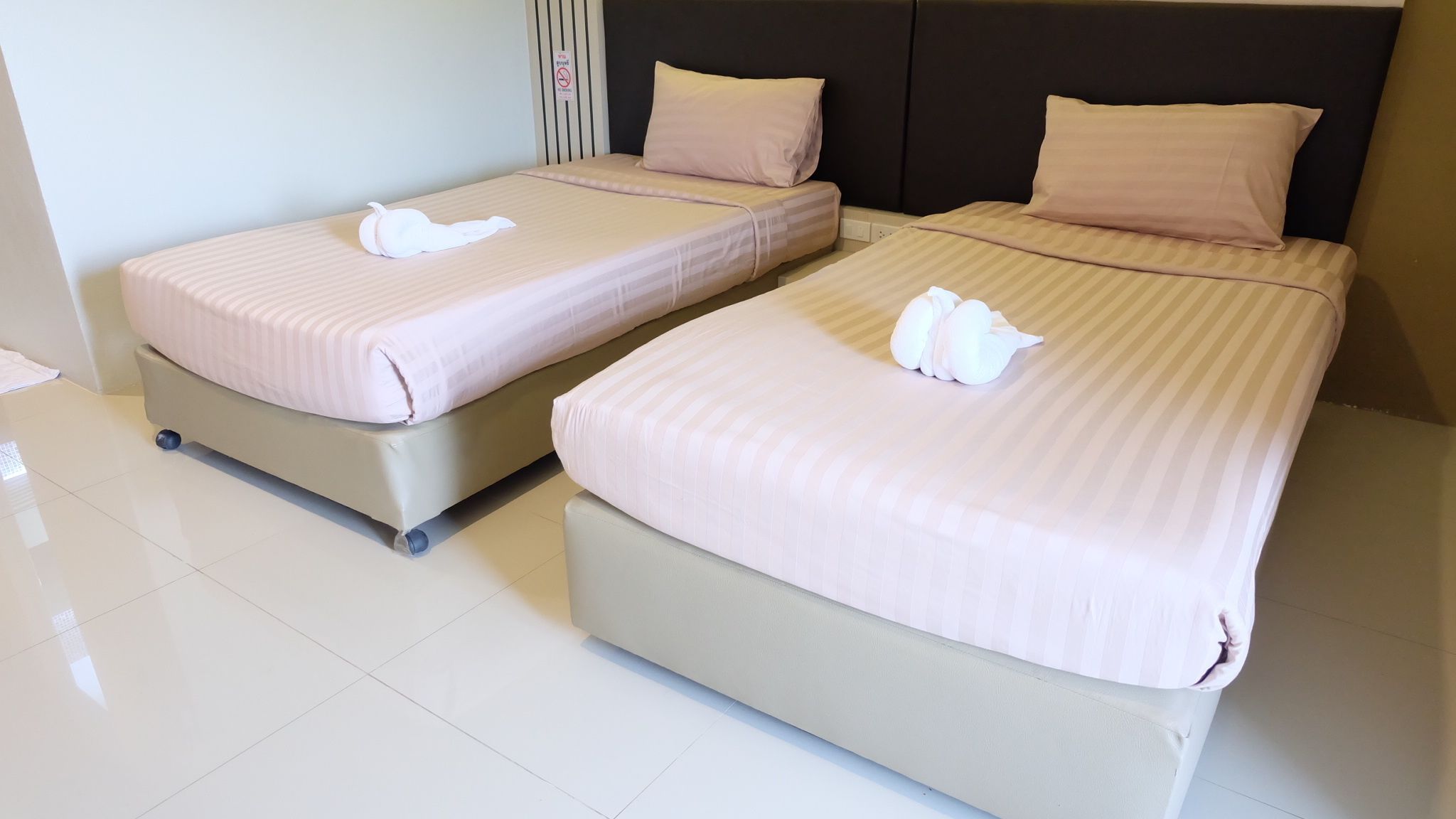 Two twin beds with matching bedding and pillows, a bedside table, and a wall-mounted sign.